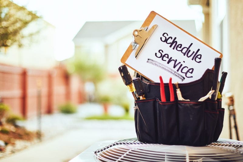 Air conditioner with maintenance tools and service reminder in residential back yard