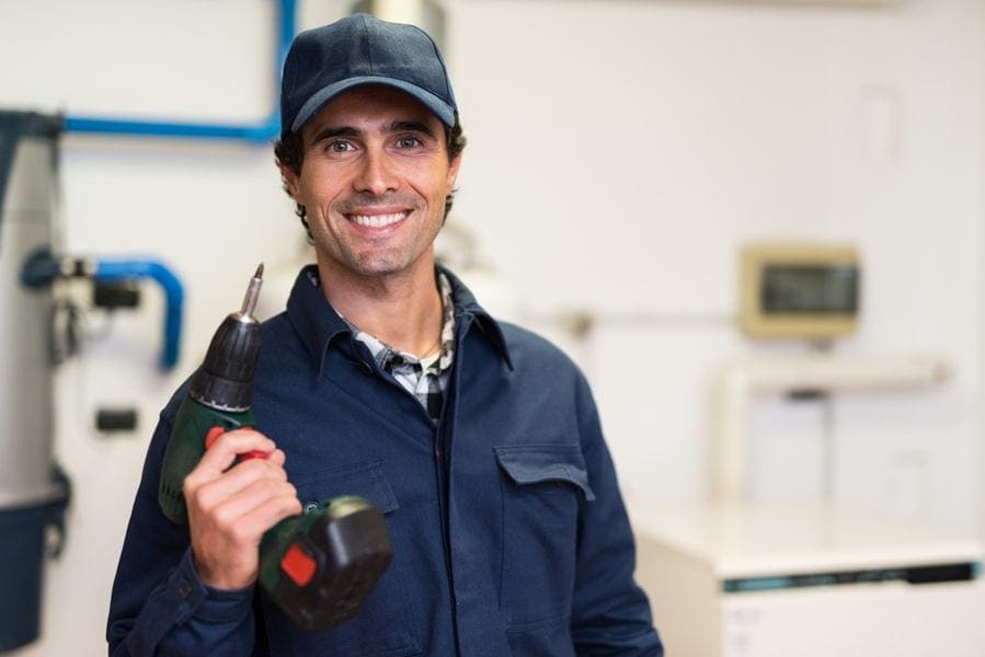 A maintenance man holds a drill. 2023 HVAC Maintenance Plans.