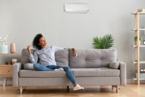 What Indoor Air Quality Accessories Can Help Keep Me Healthy? Image shows woman sitting on a grey couch and looking comfortable.